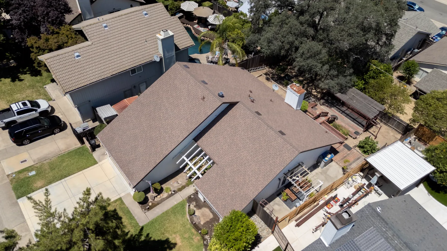Top-down drone view showing completed roof planes, valleys, vents, and chimney flashing on a Sacramento-area home